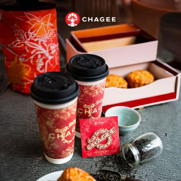 Two Chagee takeaway cups with mooncakes, tea leaves, and a Chagee tea packet on a table.